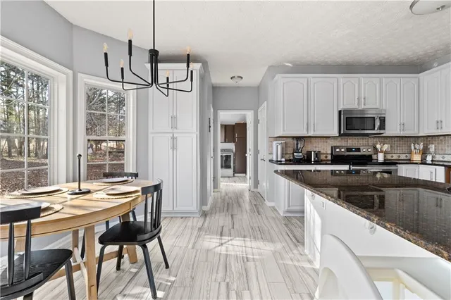 a kitchen with stainless steel appliances granite countertop a stove a sink a microwave refrigerator and a dining table with wooden floor