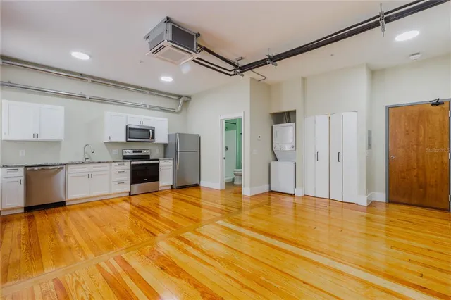 a big room with stainless steel appliances kitchen island granite countertop a refrigerator and a stove top oven