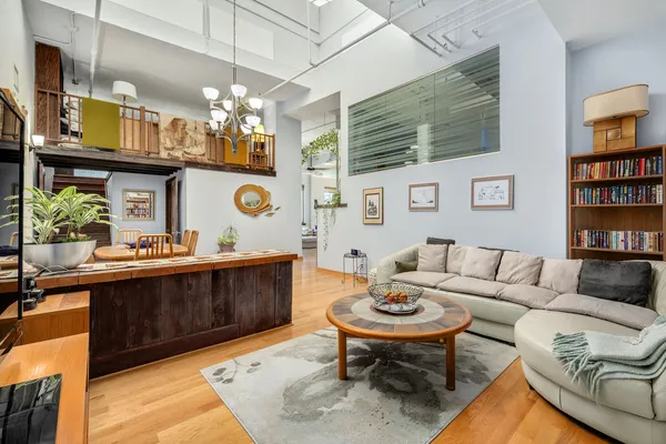 a living room with furniture a chandelier and kitchen view