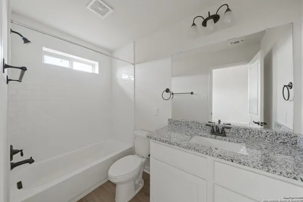 a bathroom with a granite countertop sink a toilet and shower