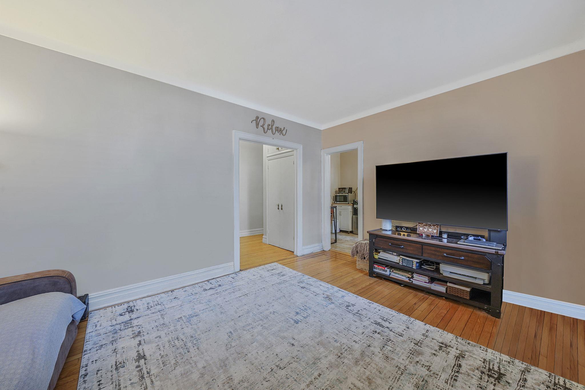83-84 116th Street, Unit 1H Queens, NY 11418 - Photo 2 of 13 a living room with furniture and a flat screen tv