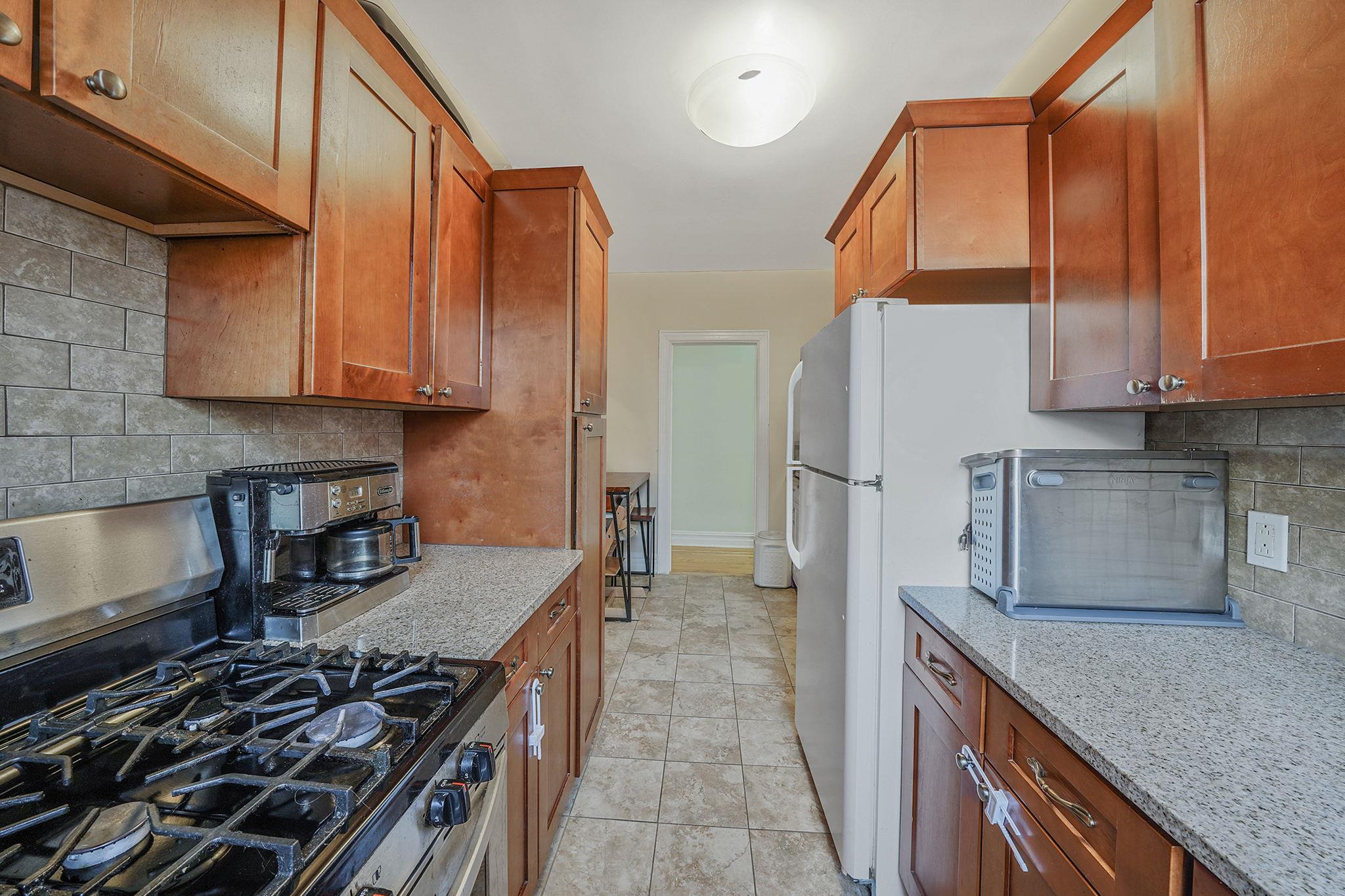 83-84 116th Street, Unit 1H Queens, NY 11418 - Photo 4 of 13 a kitchen with stainless steel appliances granite countertop a stove a sink and a refrigerator