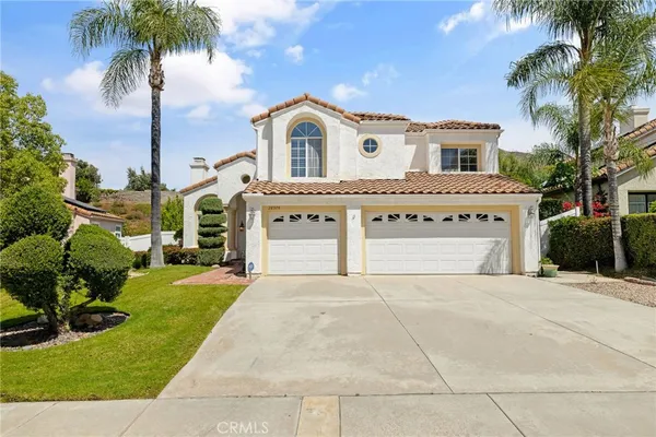a front view of a house with a garden and trees
