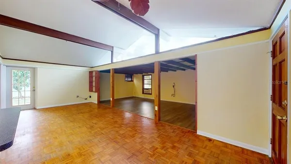 a view of an empty room with window and wooden floor