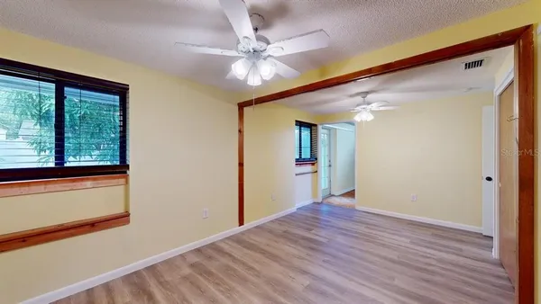 a view of an empty room with wooden floor and a window