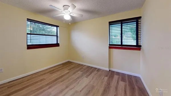 a view of empty room with wooden floor and fan