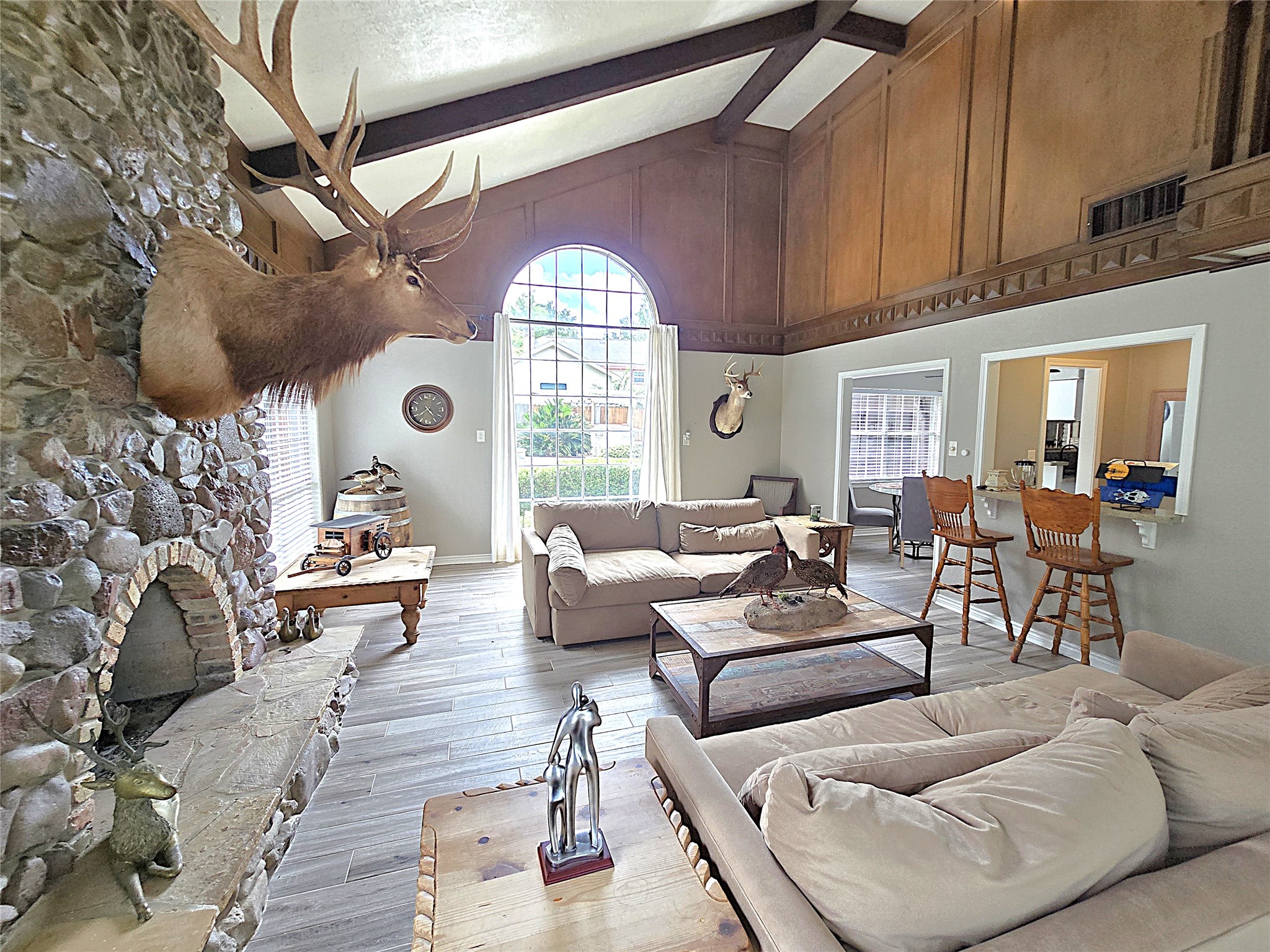 560 Brandon Road Conroe, TX 77302 - Photo 32 of 45 Spacious and inviting living room featuring a stunning stone fireplace, vaulted wood-beamed ceiling, and large arched window for abundant natural light. A perfect blend of rustic charm and modern comfort.