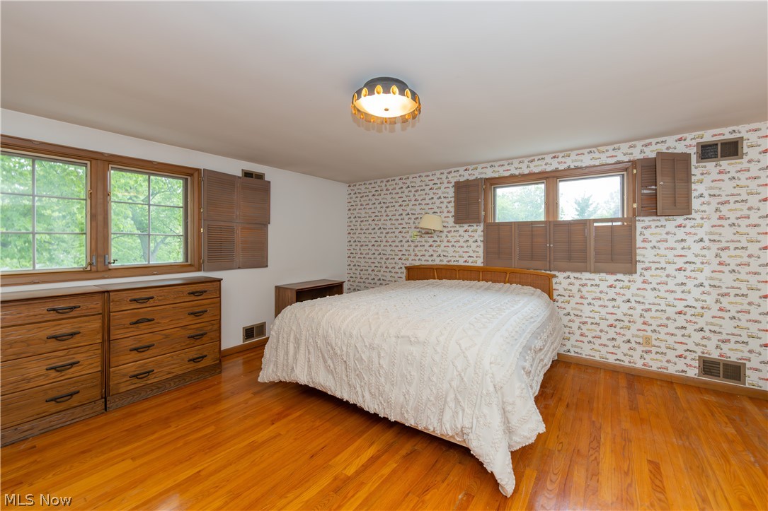 25001 Letchworth Road Beachwood, OH 44122 - Photo 34 of 50 Hardwood flooring throughout, two large windows with wooden frames and shutters, two built-in dresser units, and a ceiling-mounted light fixture