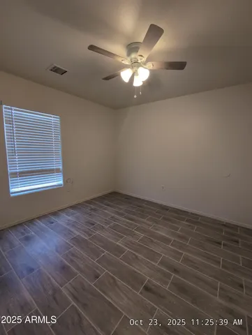 an empty room with wooden floor fan and windows