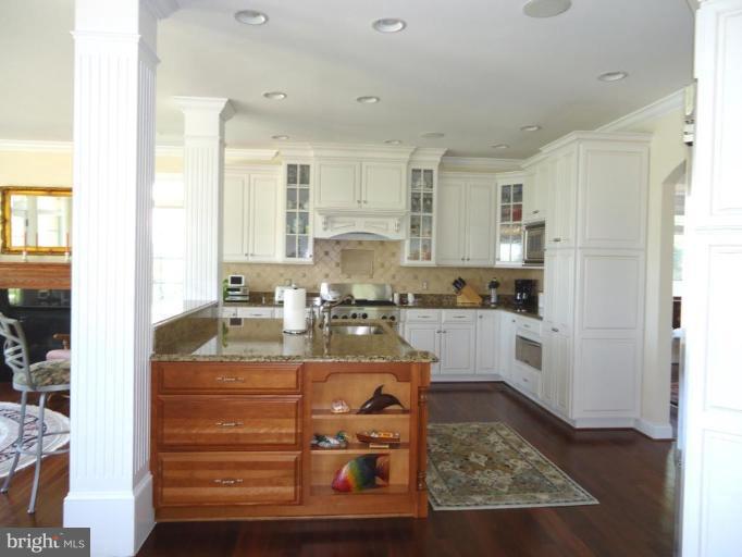 230 Bentons Pleasure Road Chester, MD 21619 - Photo 23 of 30 a kitchen with kitchen island granite countertop white cabinets and white appliances