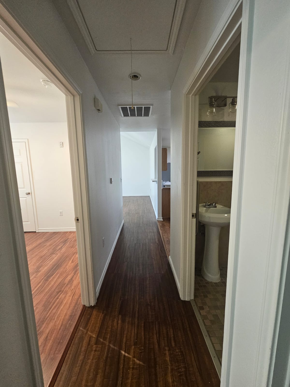 606 Trinity Street Lockhart, TX 78644 - Photo 19 of 23 Rich hardwood-style flooring extends through this central hallway, connecting various rooms within the home.