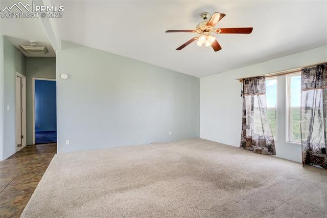 1435 Equestrian Point Yoder, CO 80864 - Photo 10 of 49 Spare room with ceiling fan, dark carpet, and lofted ceiling