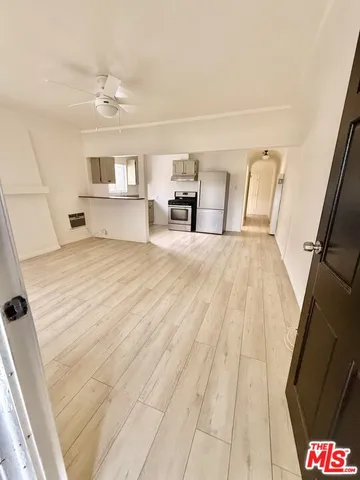 a view of an empty room with wooden floor and a window