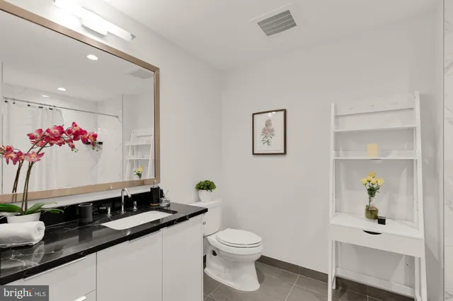 a bathroom with a granite countertop sink and a toilet