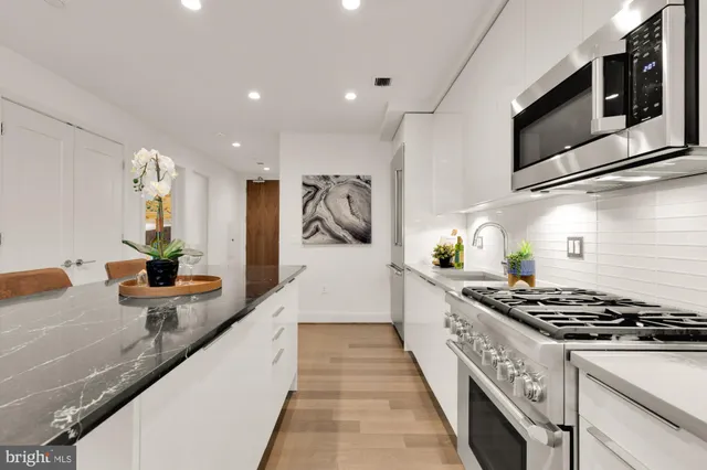 a large kitchen with stainless steel appliances granite countertop a lot of counter space and wooden floor