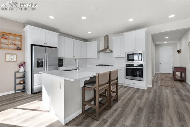 a kitchen with stainless steel appliances kitchen island granite countertop a table chairs sink refrigerator and cabinets