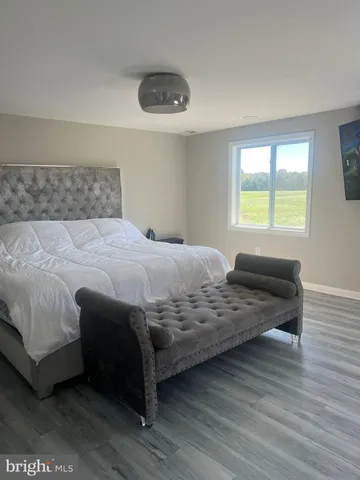 a view of an empty room with wooden floor and window
