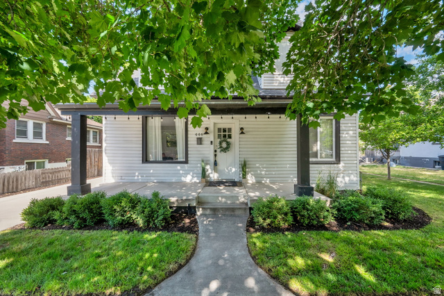 446 South 300 East Provo, UT 84606 - Photo 5 of 32 White siding exterior featuring a covered porch with dark columns, a concrete pathway, manicured front lawn, and established landscaping