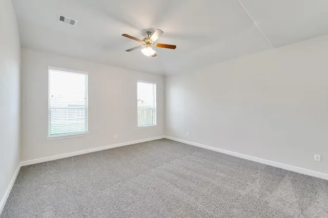 an empty room with wooden floor and a ceiling fan