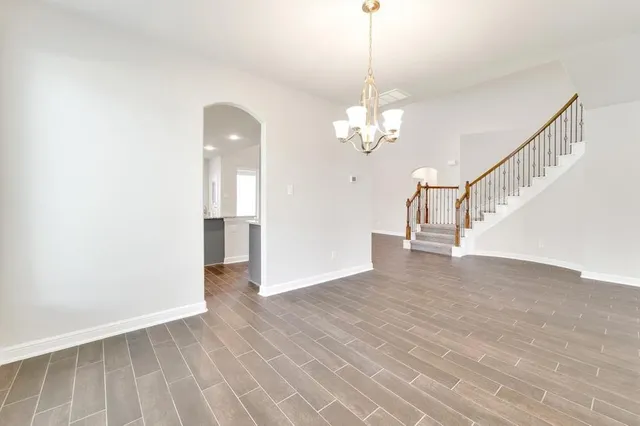 a view of empty room with wooden floor and pendant lights