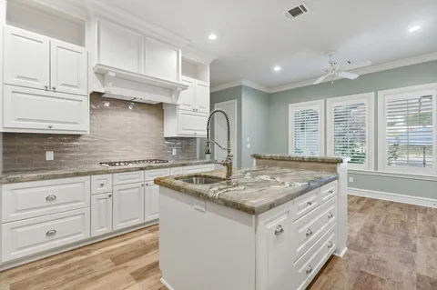 a kitchen with stainless steel appliances granite countertop a stove and white cabinets with wooden floor