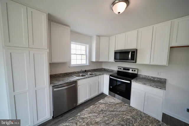 a kitchen with granite countertop white cabinets and appliances