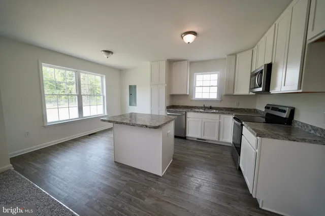 a kitchen with granite countertop a sink a counter top space and cabinets