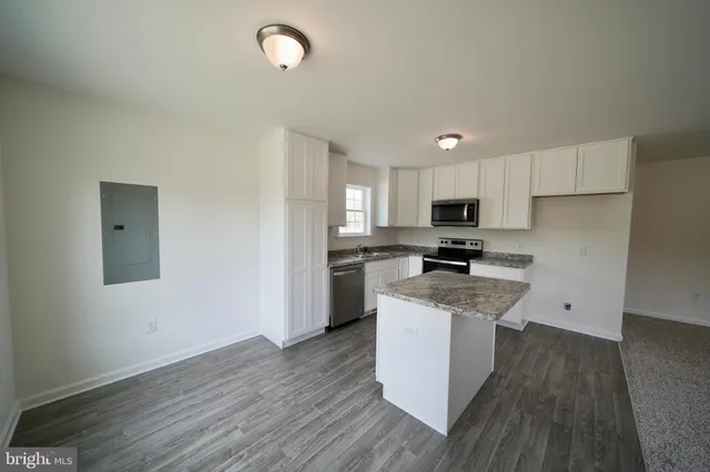 a kitchen with granite countertop a stove top oven a sink dishwasher and a refrigerator with wooden floor