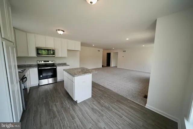 a kitchen with granite countertop a stove top oven and refrigerator