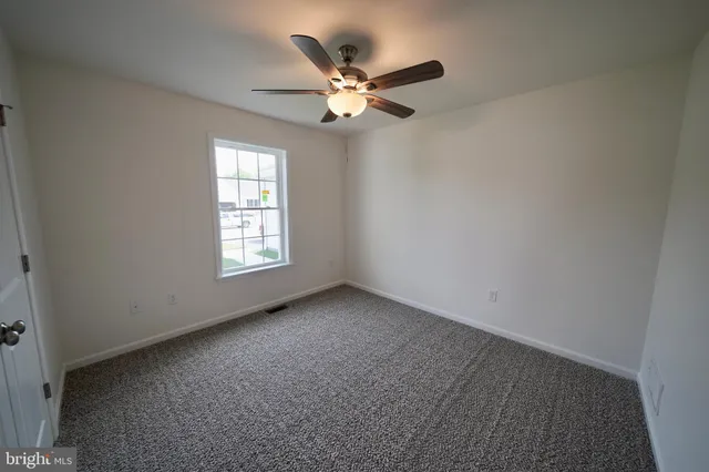 an empty room with a ceiling fan and window