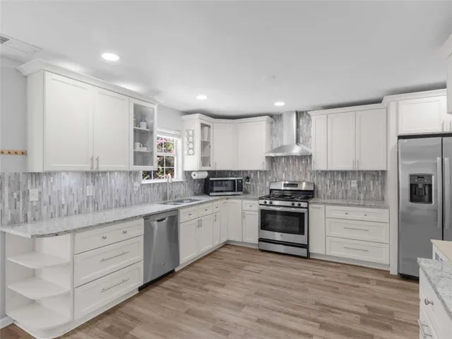 a kitchen with stainless steel appliances granite countertop a stove and white cabinets