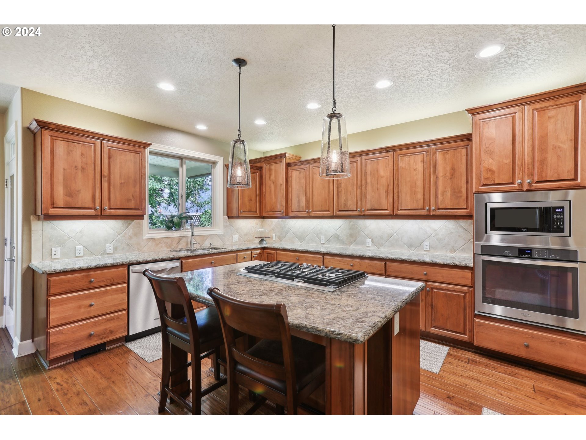 7885 Southwest Daybreak Street Wilsonville, OR 97070 - Photo 8 of 48 a kitchen with granite countertop a table chairs microwave and refrigerator