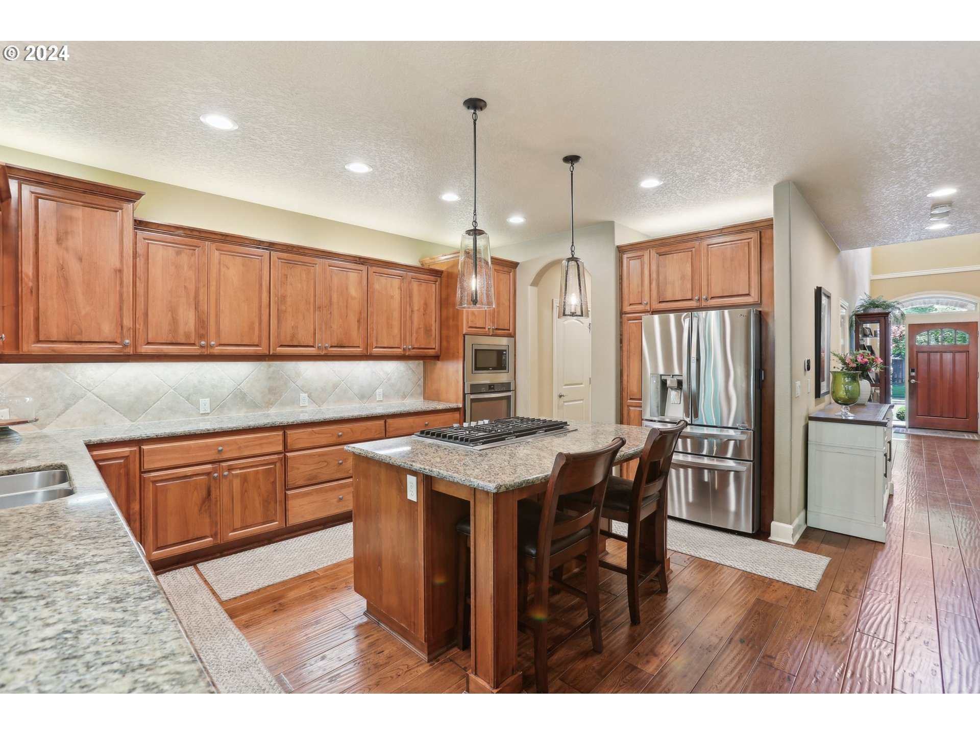 7885 Southwest Daybreak Street Wilsonville, OR 97070 - Photo 9 of 48 a kitchen with stainless steel appliances granite countertop a refrigerator a sink dishwasher a stove and a dining table with wooden floor
