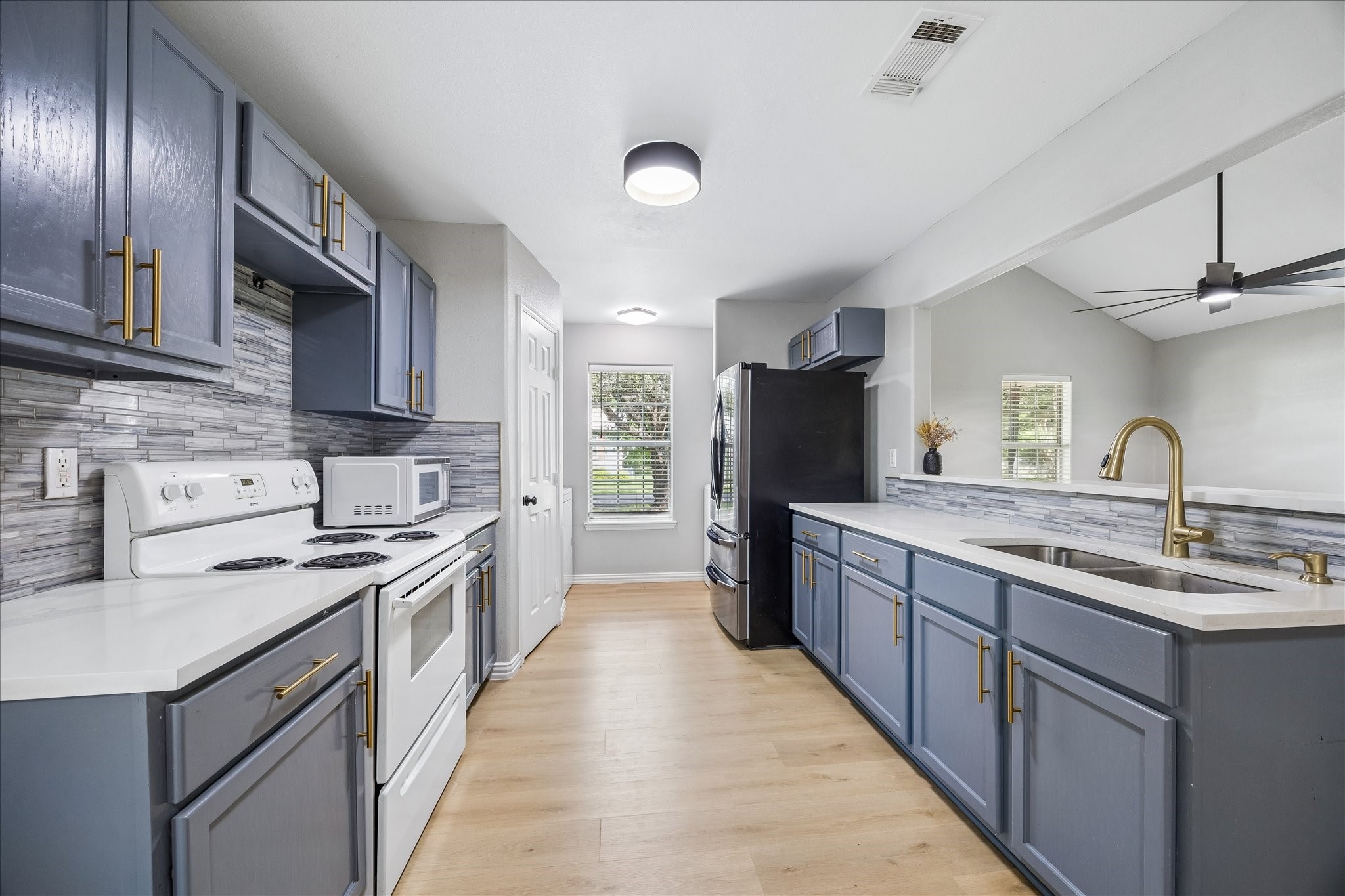 539 Anderson Street Sealy, TX 77474 - Photo 3 of 19 This modern kitchen features sleek blue cabinets with brass handles, a stylish tile backsplash, and light wood flooring. Ample counter space and a double sink with stylish lighting.