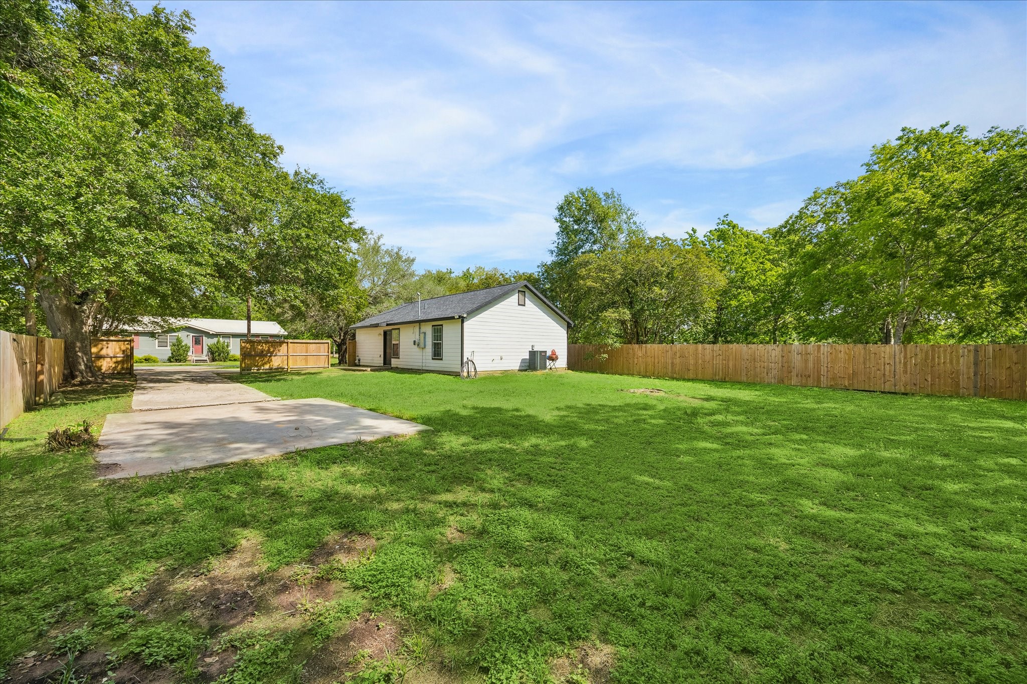539 Anderson Street Sealy, TX 77474 - Photo 5 of 19 Spacious backyard with a well-maintained lawn, surrounded by a wooden fence. The yard is bordered by mature trees, offering a private and serene setting.
