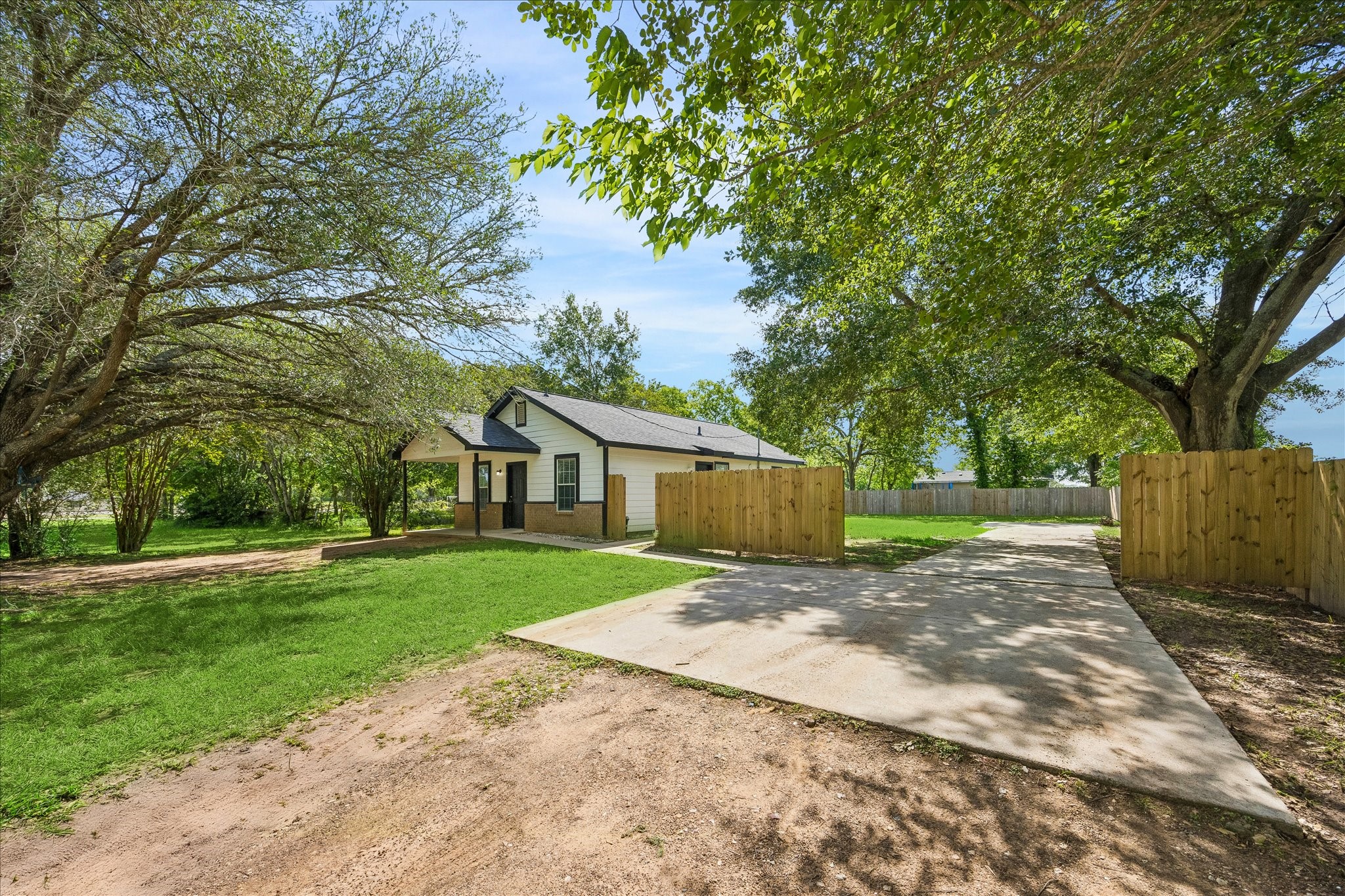 539 Anderson Street Sealy, TX 77474 - Photo 6 of 19 Charming single-story home with a welcoming front porch, nestled among mature trees. Features a spacious driveway, fenced-in yard, and lush green lawn, perfect for privacy and outdoor activities.