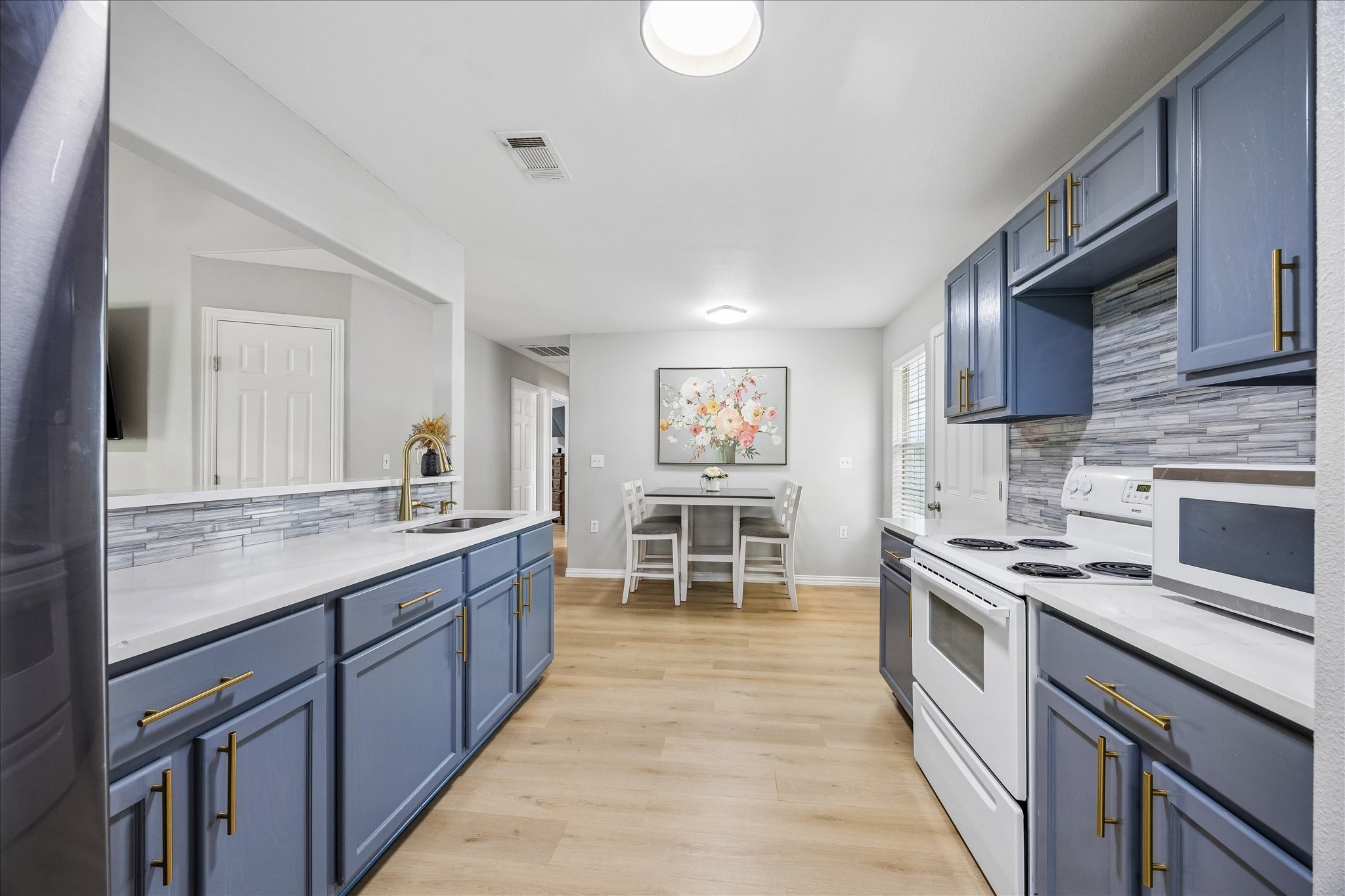539 Anderson Street Sealy, TX 77474 - Photo 10 of 19 This modern kitchen features sleek blue cabinets with brass handles, a stylish tile backsplash, and light wood flooring. Ample counter space and a double sink with stylish lighting.