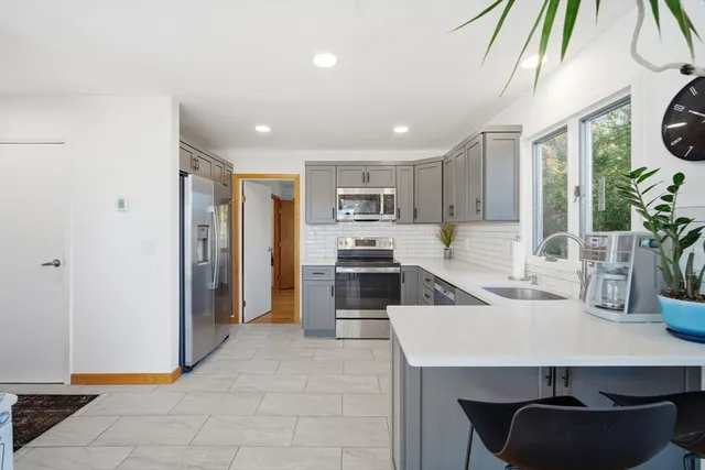 a kitchen with stainless steel appliances a sink a stove a refrigerator cabinets and a dining table