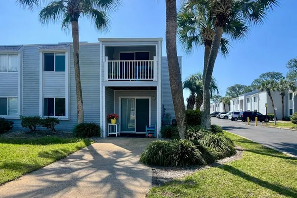 a front view of a house with garden and trees