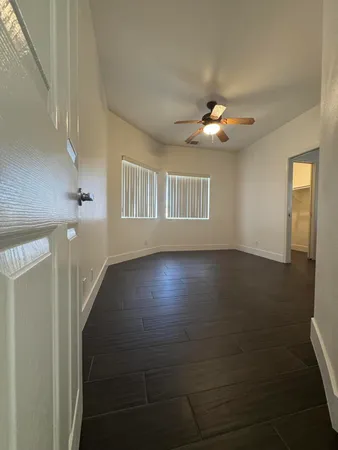 a view of an empty room with wooden floor and a chandelier fan