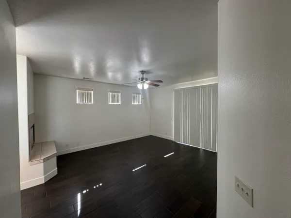 an empty room with wooden floor chandelier fan and windows