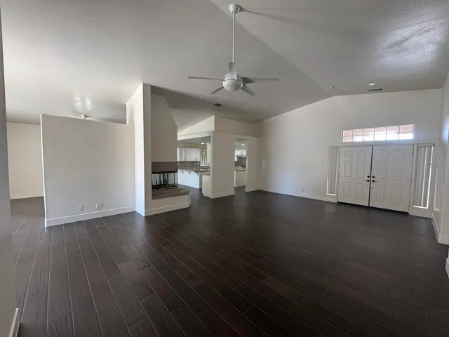 a view of an empty room with wooden floor and a window