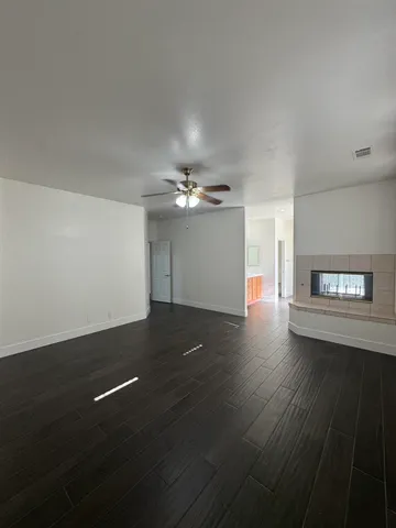 a view of an empty room with wooden floor and a chandelier fan