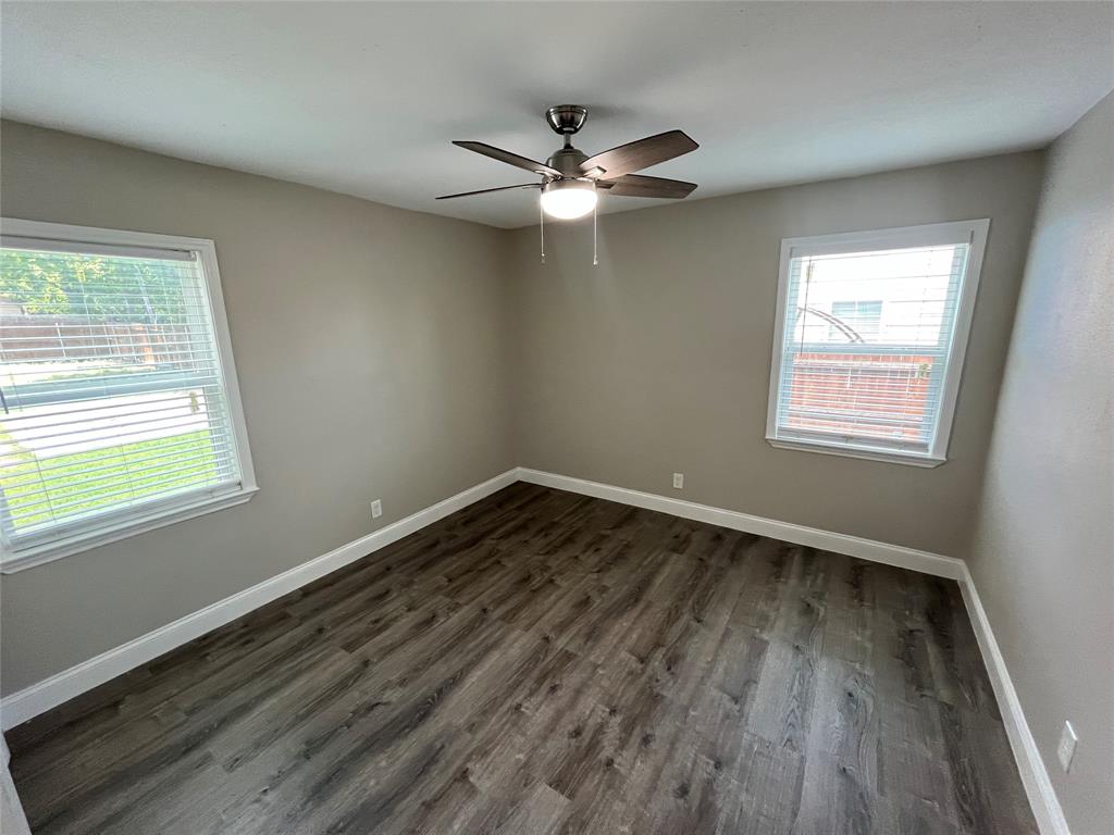 7046 Forney Road Dallas, TX 75227 - Photo 16 of 19 Room featuring wood-finish flooring, two windows with blinds, a ceiling fan with integrated lighting, neutral wall paint, and white baseboards