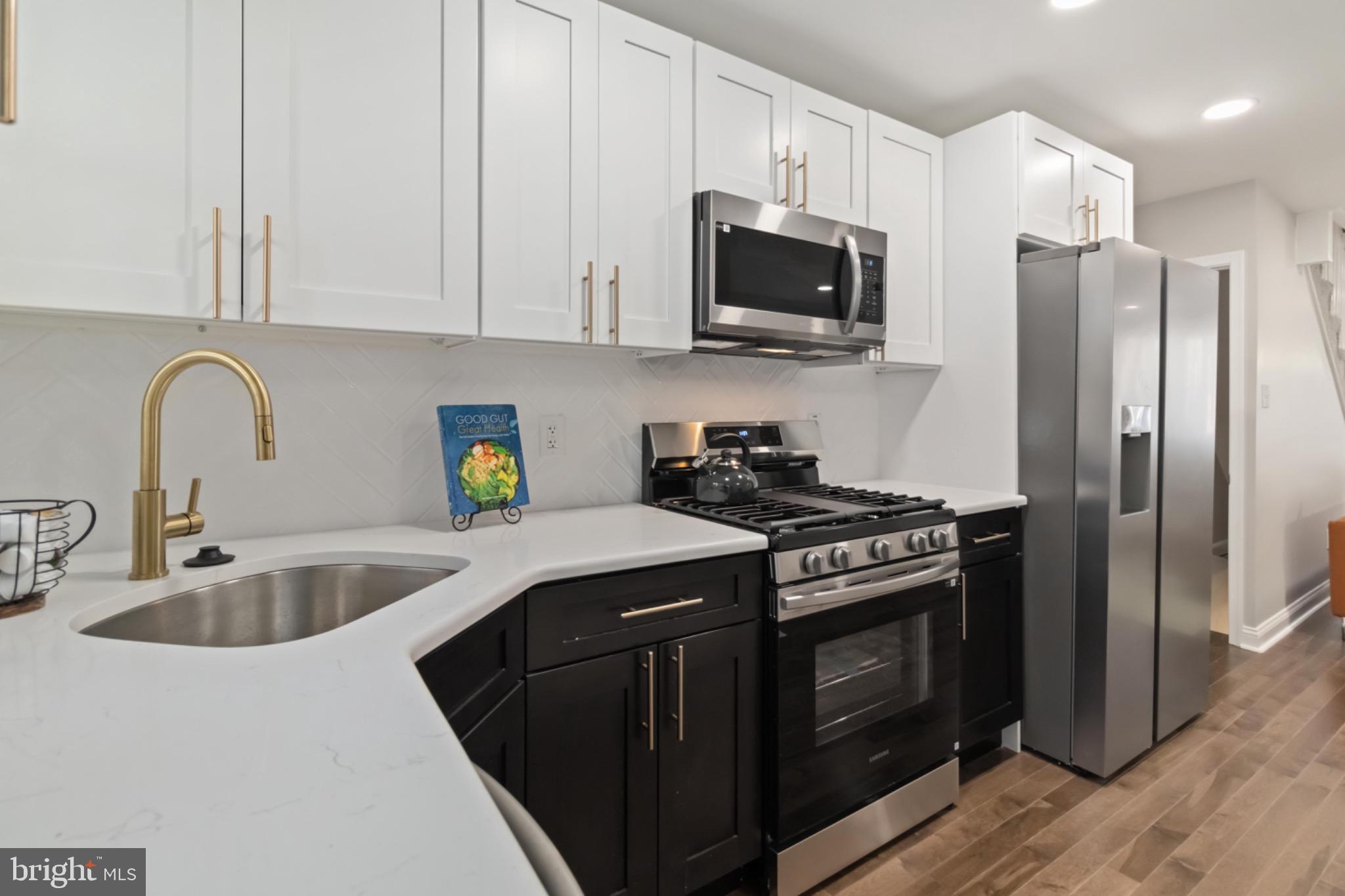 7724 Fayette Street Philadelphia, PA 19150 - Photo 16 of 33 a kitchen with stainless steel appliances granite countertop a stove a sink dishwasher a refrigerator and a microwave oven with wooden floor