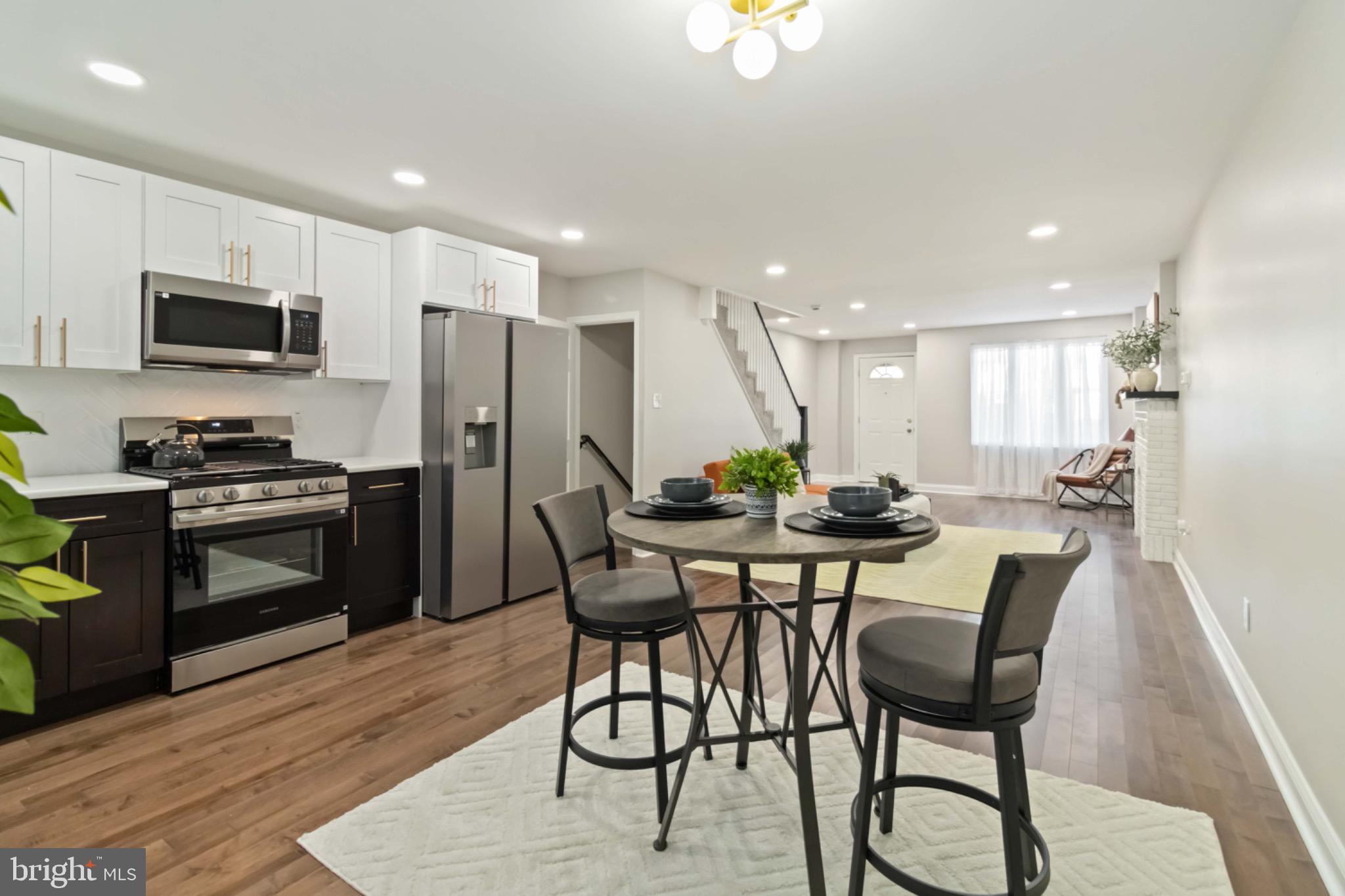 7724 Fayette Street Philadelphia, PA 19150 - Photo 9 of 33 a kitchen with stainless steel appliances kitchen island granite countertop a refrigerator a stove a microwave oven a sink with island and chairs in it
