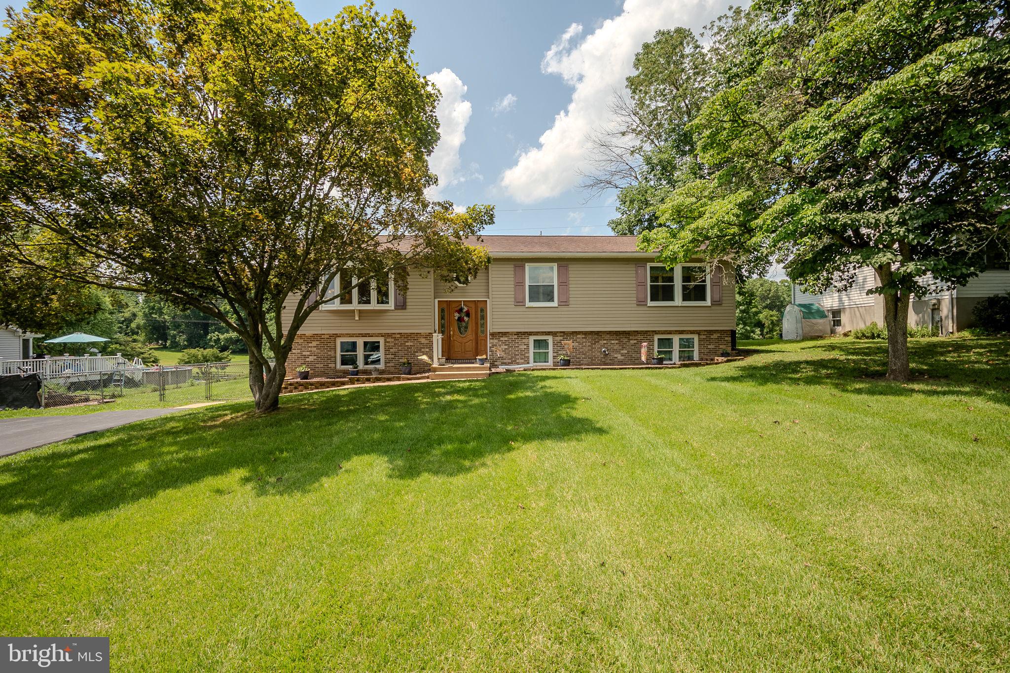 a view of a house with a big yard and large tree