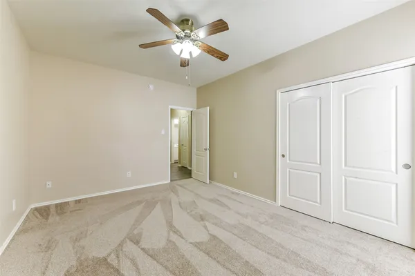 an empty room with chandelier fan and windows