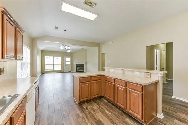 a large kitchen with stainless steel appliances granite countertop a sink dishwasher a stove and white cabinets with wooden floor