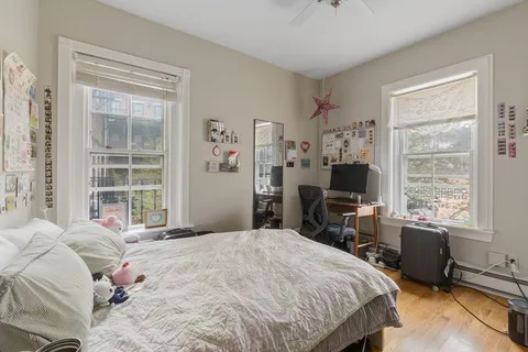 a bedroom with a bed large window and a flat tv screen